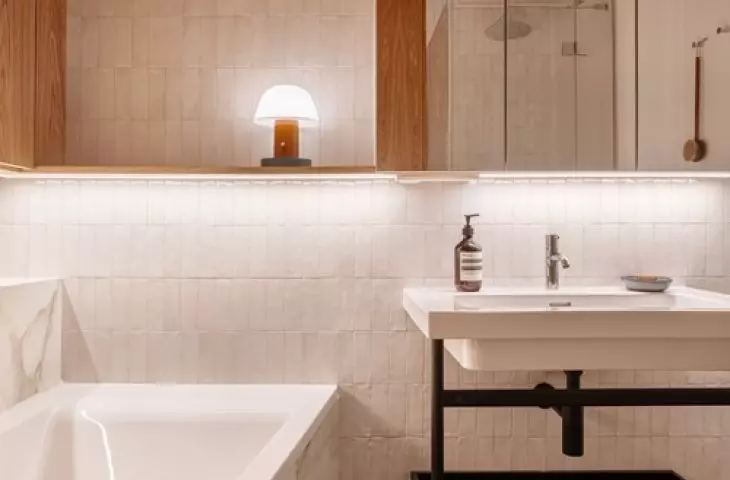 The bathroom contrasts with the rest, offering bright tiles and a marble bathtub, with a blue and white floor in a geometric pattern