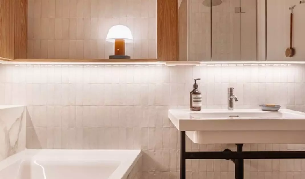 Łazienka kontrastuje z resztą, oferując jasne płytki i marmurową wannę, z niebiesko-białą podłogą w geometrycznym wzorze