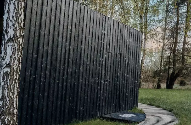 drzwi wejściowe do domku ukryte są w elewacji pokrytej opalanymi świerkowymi deskami (japońska technika Shou Sugi Ban)