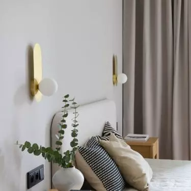 The bedroom is dominated by shades of beige, juxtaposed with wooden furniture and an upholstered bed 
