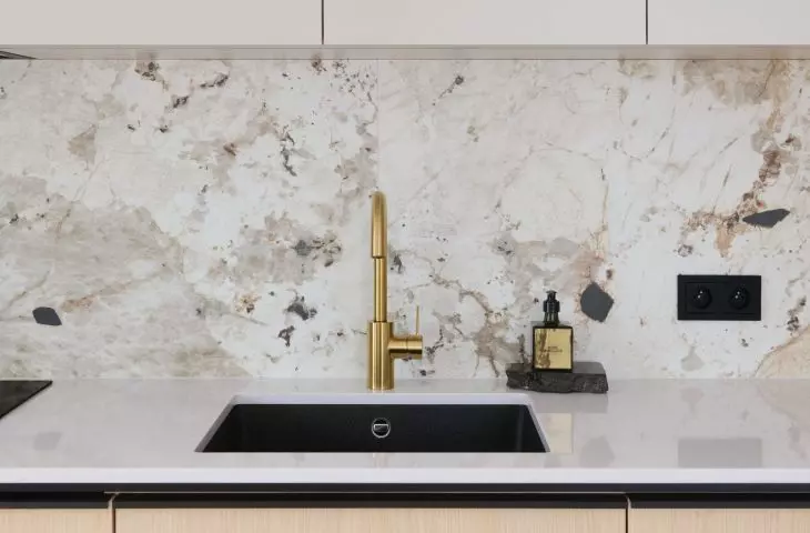 In the kitchen, a gold faucet and black appliances add elegance
