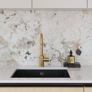 In the kitchen, a gold faucet and black appliances add elegance