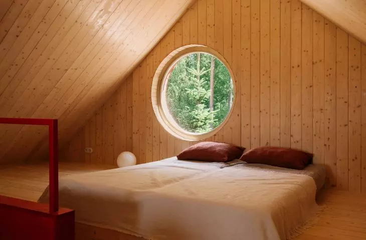 A circular window on the mezzanine frames a picturesque view of the forest