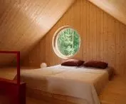 A circular window on the mezzanine frames a picturesque view of the forest