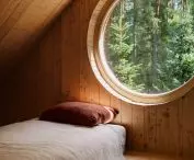 A circular window on the mezzanine frames a picturesque view of the forest