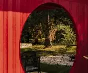 A circular cutout in the pergola frames the view of a nearby tree