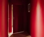 wyrazista strefa wejściowa (w soczystym odcieniu czerwieni są zarówno ściany, jak i sufit), „zmiękczona” jest wizualnie poprzez wyblone narożniki