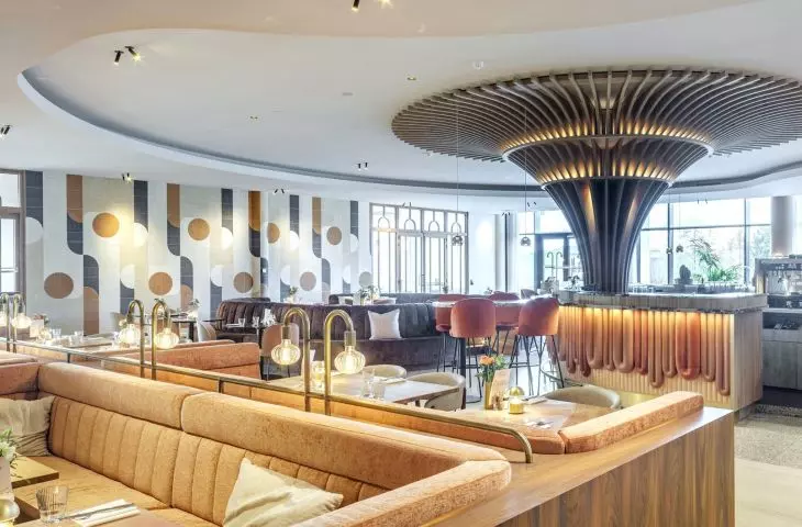 Geometric shapes as muntins in doors, the shapes of bar shelves or the pattern of the wallpaper in the restaurant, together with stylized chairs and armchairs, transport hotel guests to the design world of the 1970s era