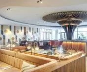 Geometric shapes as muntins in doors, the shapes of bar shelves or the pattern of the wallpaper in the restaurant, together with stylized chairs and armchairs, transport hotel guests to the design world of the 1970s era