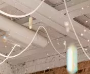 The technical character of the ceiling is broken by decorative lighting - diamond-like pendant lights, reflective crystals and luminous garlands