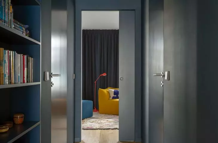 The corridor connecting the living room zone with the bedroom is kept in a deep shade of navy blue