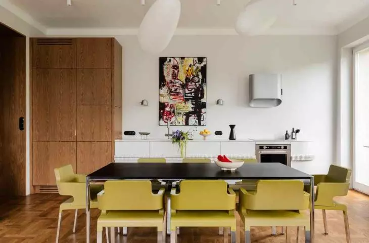 In the dining room, the main fiddle is played by a black USM Haller designer table surrounded by geometric chairs in a shade of lime green designed by Christophe Marchand.