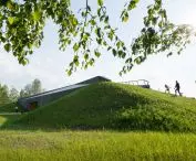 obłożoną drewnem bryłę otaczają zielone skarpy