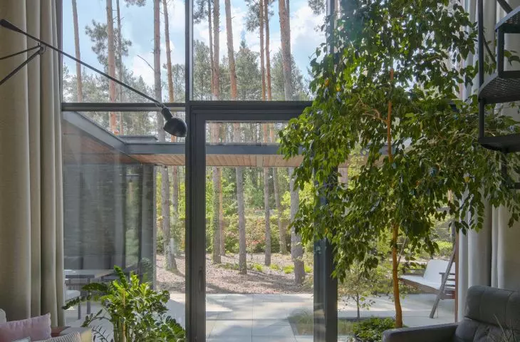 Two-storey living area with large glazing framing views of the forest