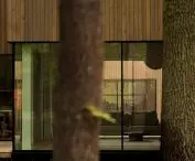 The palette of materials remains understated and in harmony with the surroundings—natural textures echo the colors of tree trunks, shadows, and forest light