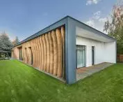 low, one-storey single-family house with a cuboidal body is diversified by wooden razor blades