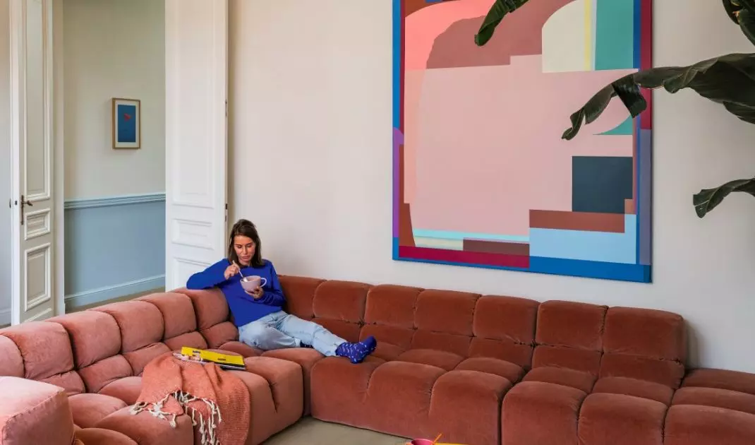 A soft, quilted sofa, light-colored flooring, and graphic accessories demonstrate how textures can create a retro vibe in an interior without resorting to overt styling