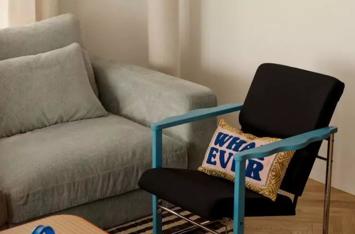 The calm, understated atmosphere of the living room is broken up by the blue of the armchair, the patterned rug, and whimsical details