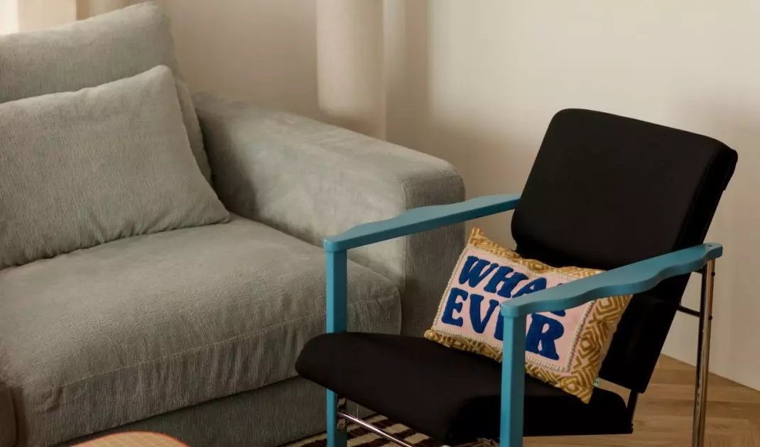 The calm, understated atmosphere of the living room is broken up by the blue of the armchair, the patterned rug, and whimsical details