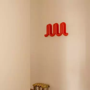 The hallway serves as a colorful introduction to the apartment—with a striking floor and a spotted stool