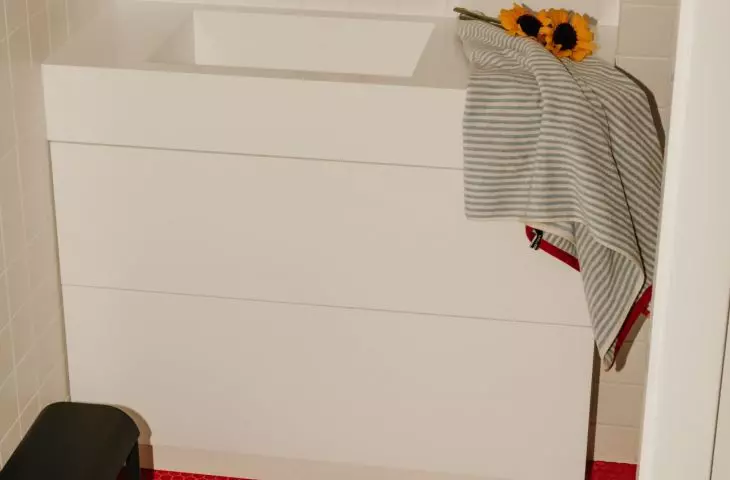 The bright bathroom is accented by a red pattern on the floor and graphic accents
