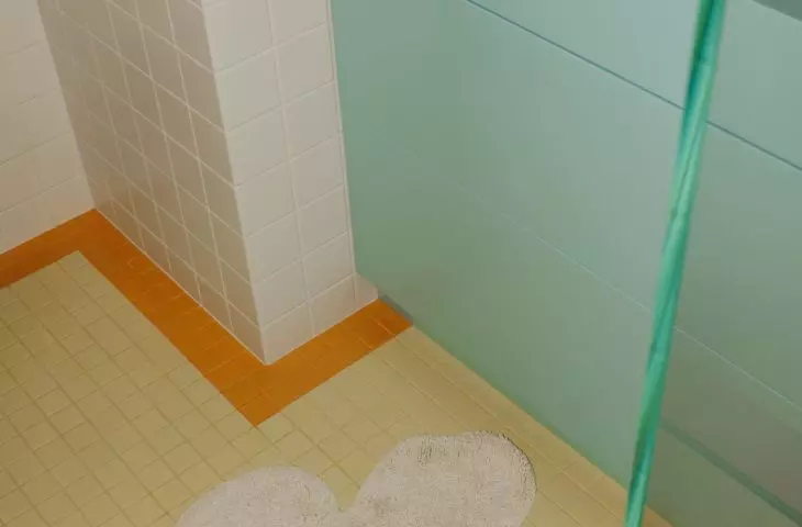A blue sink, yellow floor, and a flower-shaped rug create a bathroom with a light, airy feel.