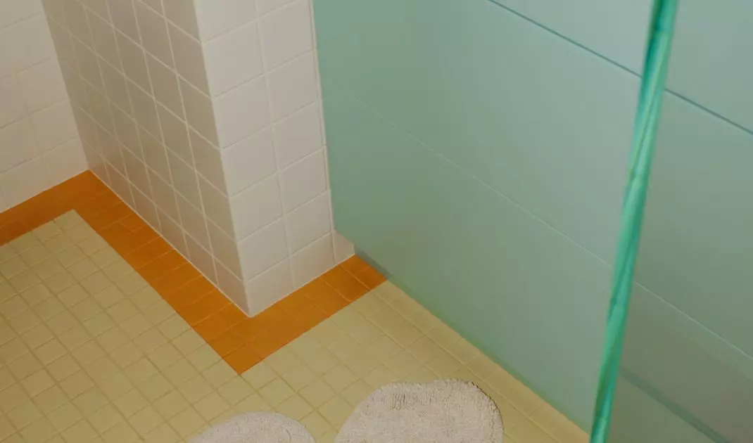 A blue sink, yellow floor, and a flower-shaped rug create a bathroom with a light, airy feel.