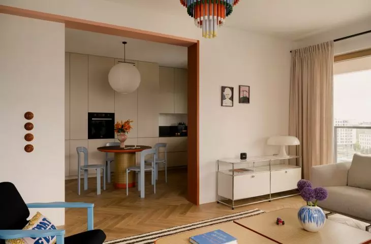 The living area combines a calm base with bold pops of color that lead toward the dining room and kitchen