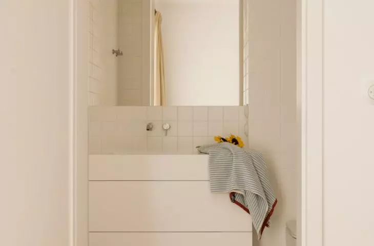 The bright bathroom is accented by a red pattern on the floor and graphic accents 