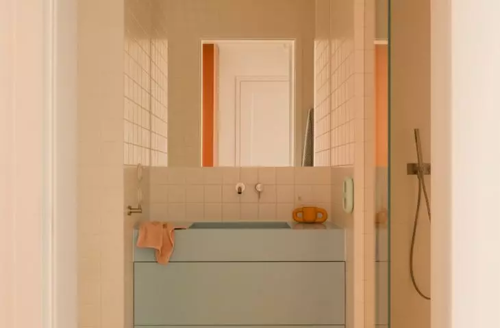 A blue sink, yellow floor, and a flower-shaped rug create a bathroom with a light, airy feel