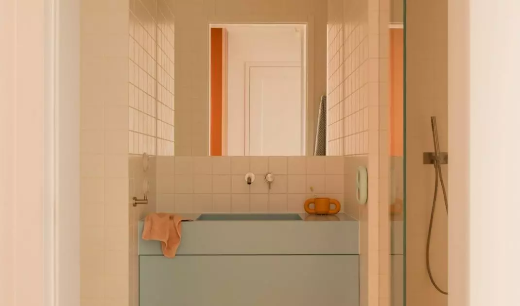 A blue sink, yellow floor, and a flower-shaped rug create a bathroom with a light, airy feel