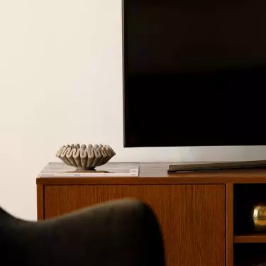 A wooden TV cabinet adds warmth to the living room and brings a mid-century vibe to the space