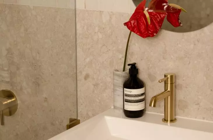 The bathroom is warmed up by wooden cabinet fronts and gold-colored fixtures