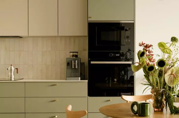 The green kitchen is the highlight of the apartment and flows naturally into the dining area