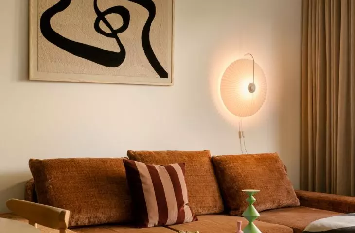 A rust-colored sofa, soft lighting, and mid-century-style details give the living room a warm, homey feel.