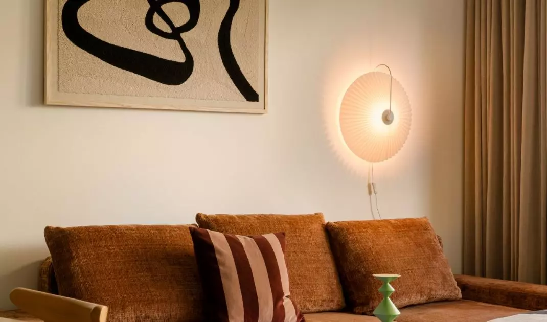 Rdzawa sofa, miękkie światło i detale w klimacie mid-century nadają salonowi ciepły, domowy charakter.