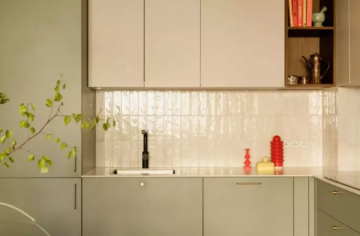 Sage-colored kitchen cabinet fronts pair well with light wood and glossy tiles