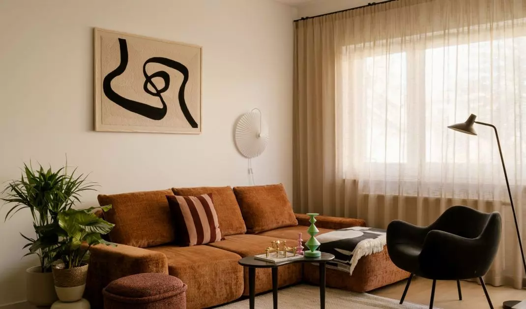 W salonie klimat mid-century jest najbardziej wyczuwalny — w obłych formach, drewnianych meblach i dekoracyjnych detalach