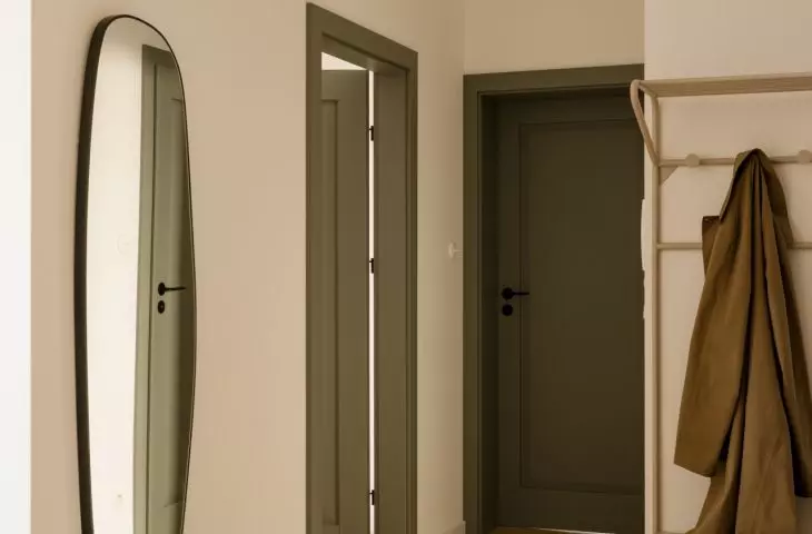 The entryway features a calm color palette, accented by the green of the door and black details