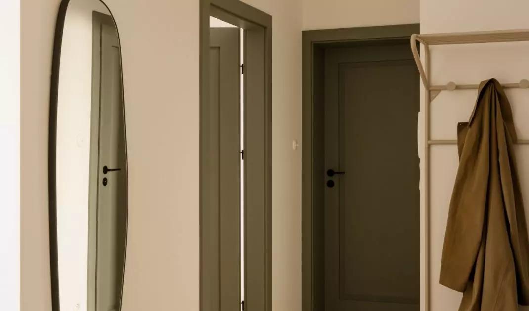 The entryway features a calm color palette, accented by the green of the door and black details