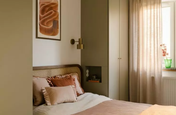 Soft textiles, a woven headboard, and a rust-colored throw create an intimate atmosphere in the bedroom