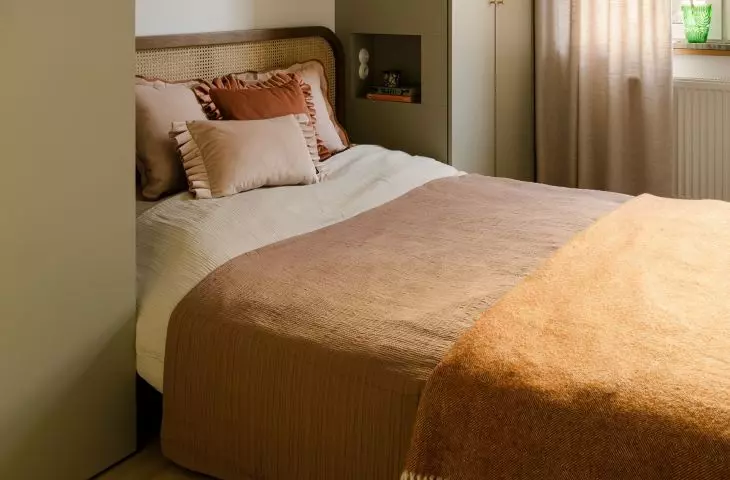 Wicker, wood, and muted green tones give the bedroom a calm, slightly retro feel