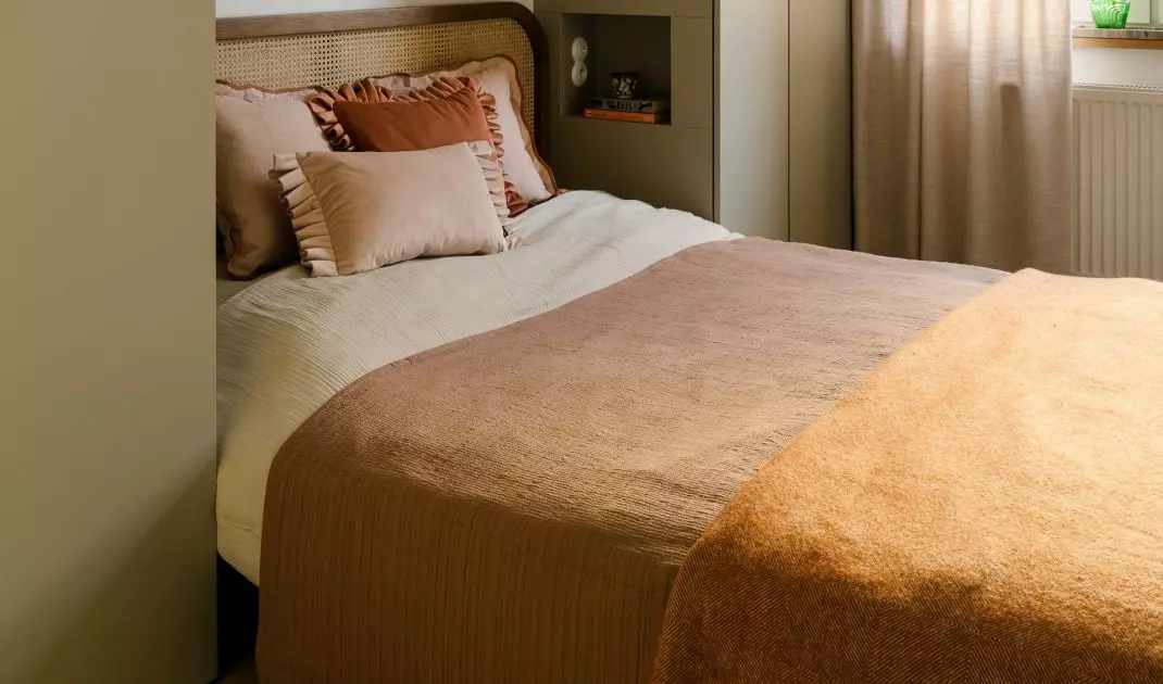 Wicker, wood, and muted green tones give the bedroom a calm, slightly retro feel