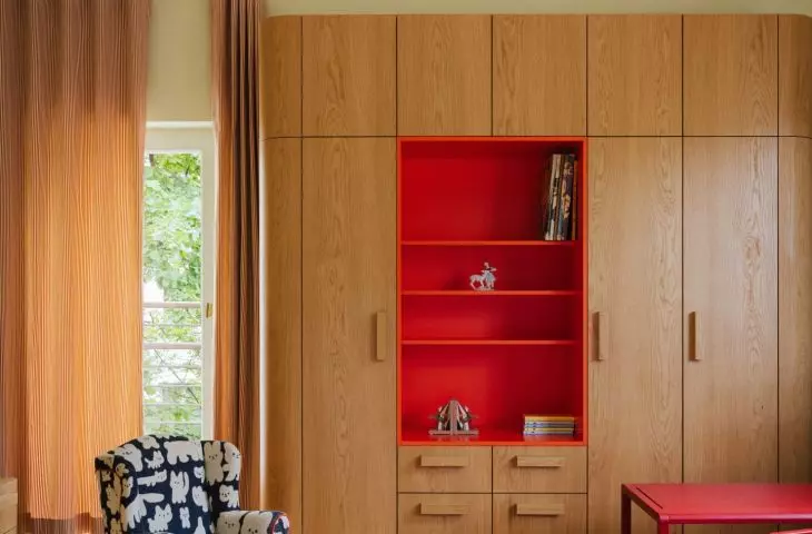The children's room combines the warmth of wood with bold accents of red and orange. This makes the interior cheerful without being overly sweet.