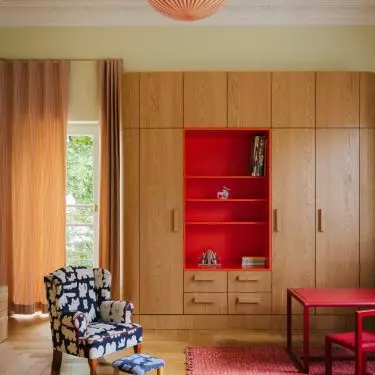 The children's room combines the warmth of wood with bold accents of red and orange. This makes the interior cheerful without being overly sweet.
