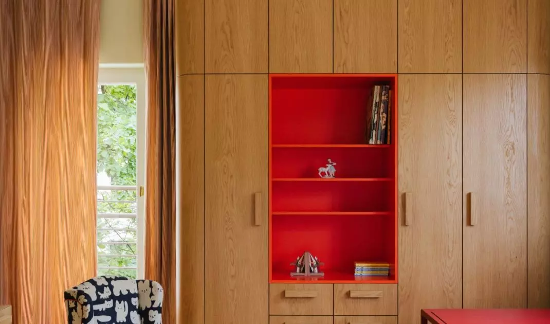 The children's room combines the warmth of wood with bold accents of red and orange. This makes the interior cheerful without being overly sweet.