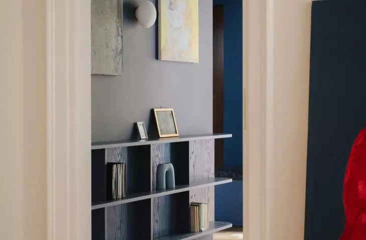 The dark navy blue entryway serves as an atmospheric introduction to the apartment—beyond it lie brighter rooms