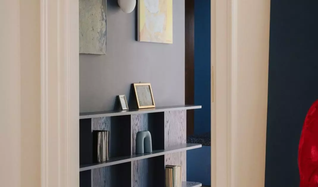 The dark navy blue entryway serves as an atmospheric introduction to the apartment—beyond it lie brighter rooms