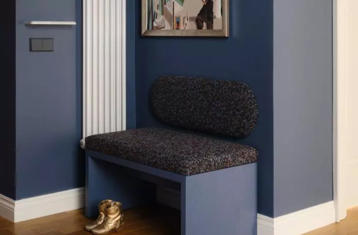 The deep navy blue hue, the artwork, and the soft seating make the entryway not just a passageway, but a full-fledged part of the home