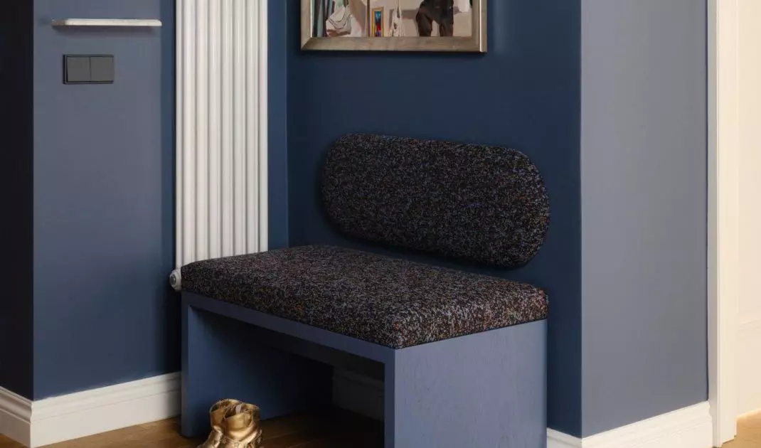 The deep navy blue hue, the artwork, and the soft seating make the entryway not just a passageway, but a full-fledged part of the home